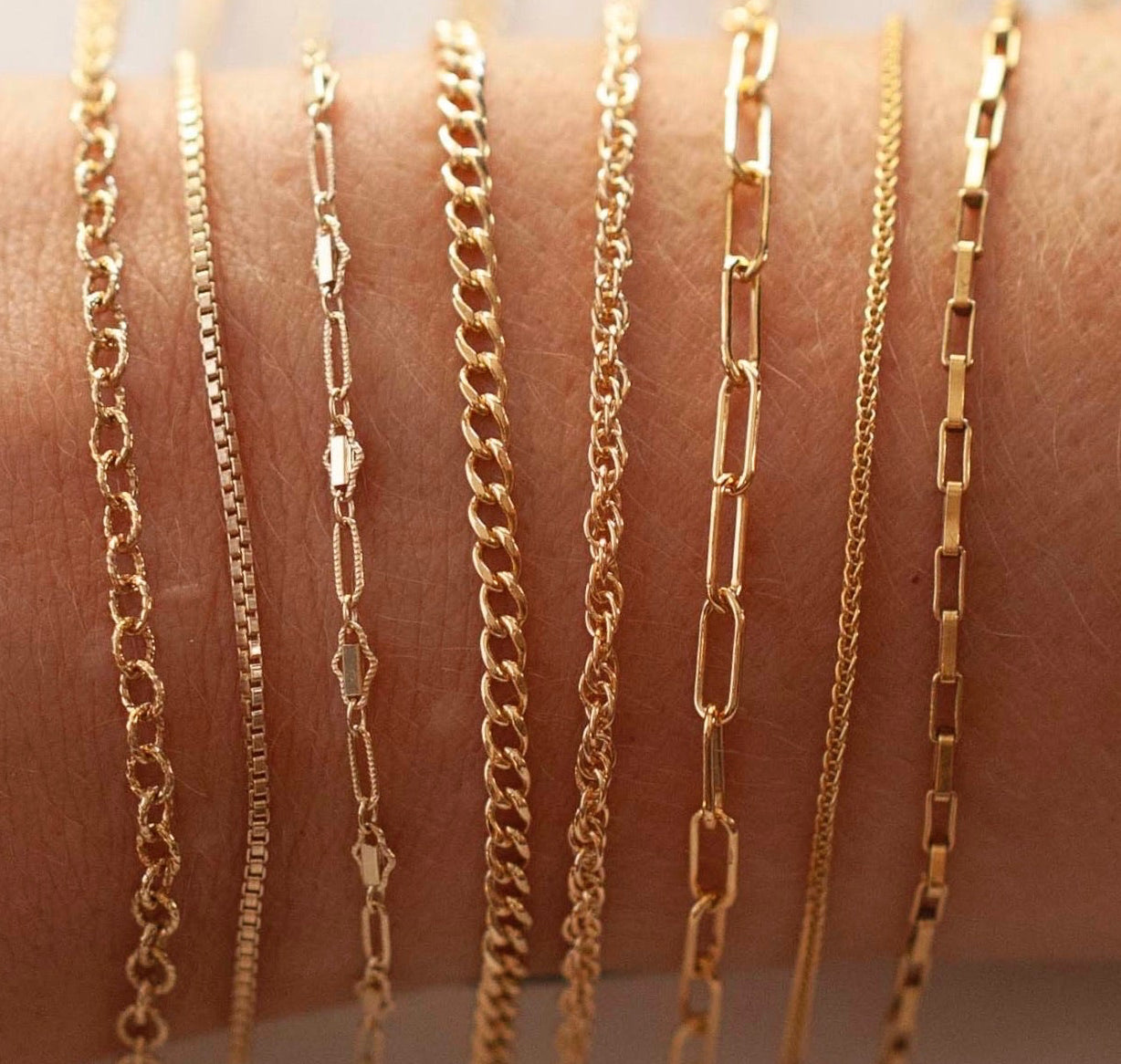 Gold chains of various designs on a person's arm
